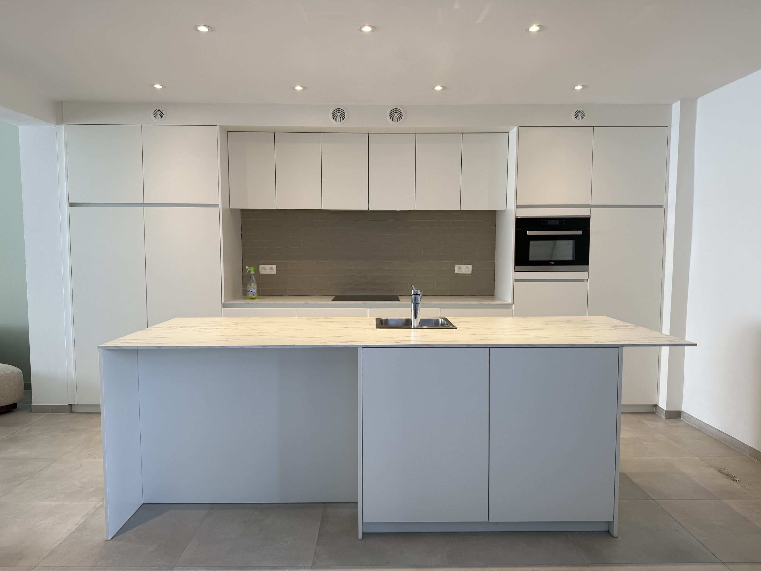 Lichte keuken met witte kastfronten en kookeiland voor de transformatie