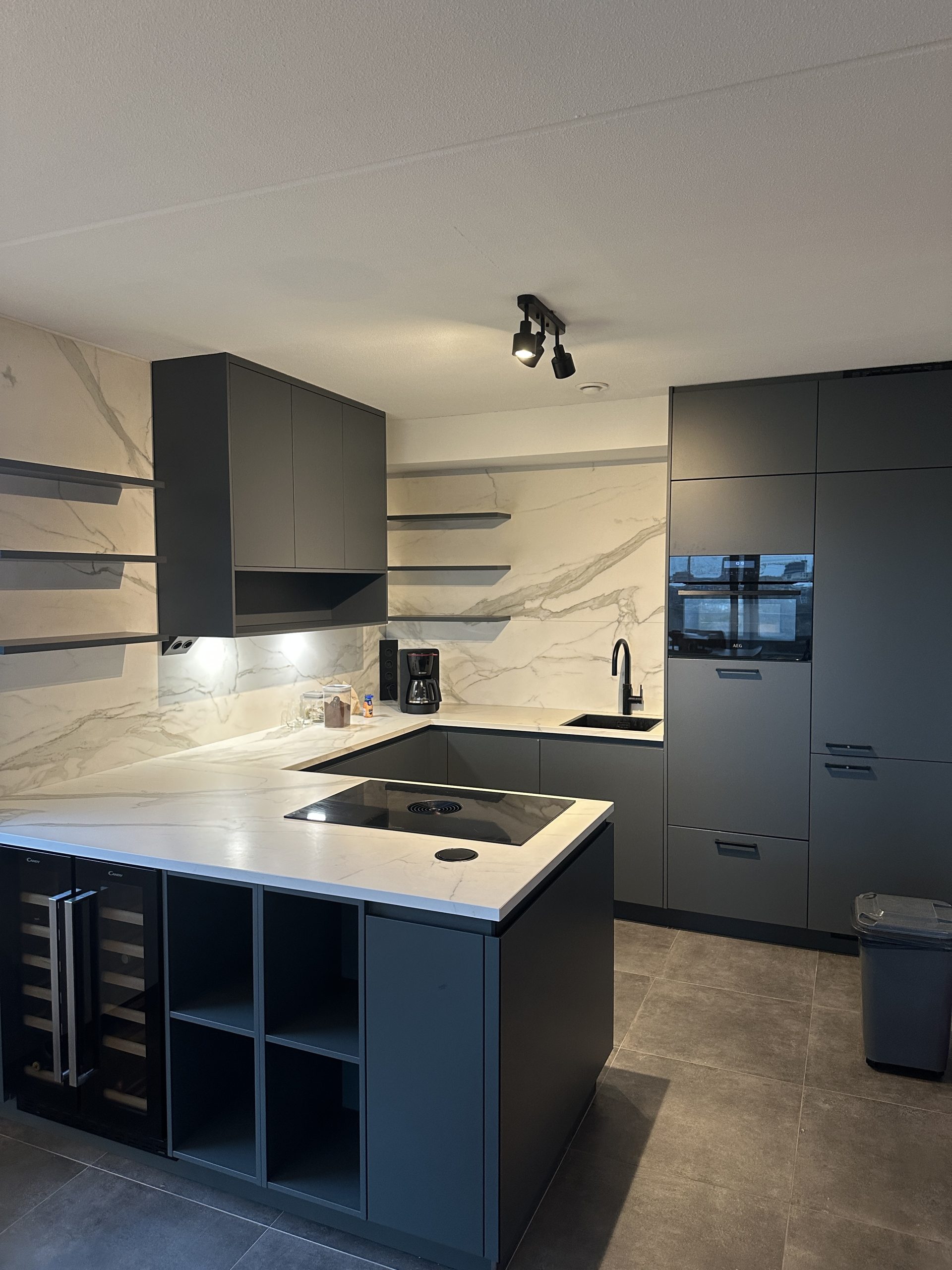 Antraciete keuken met matte fronten en een lichte marmerlook achterwand