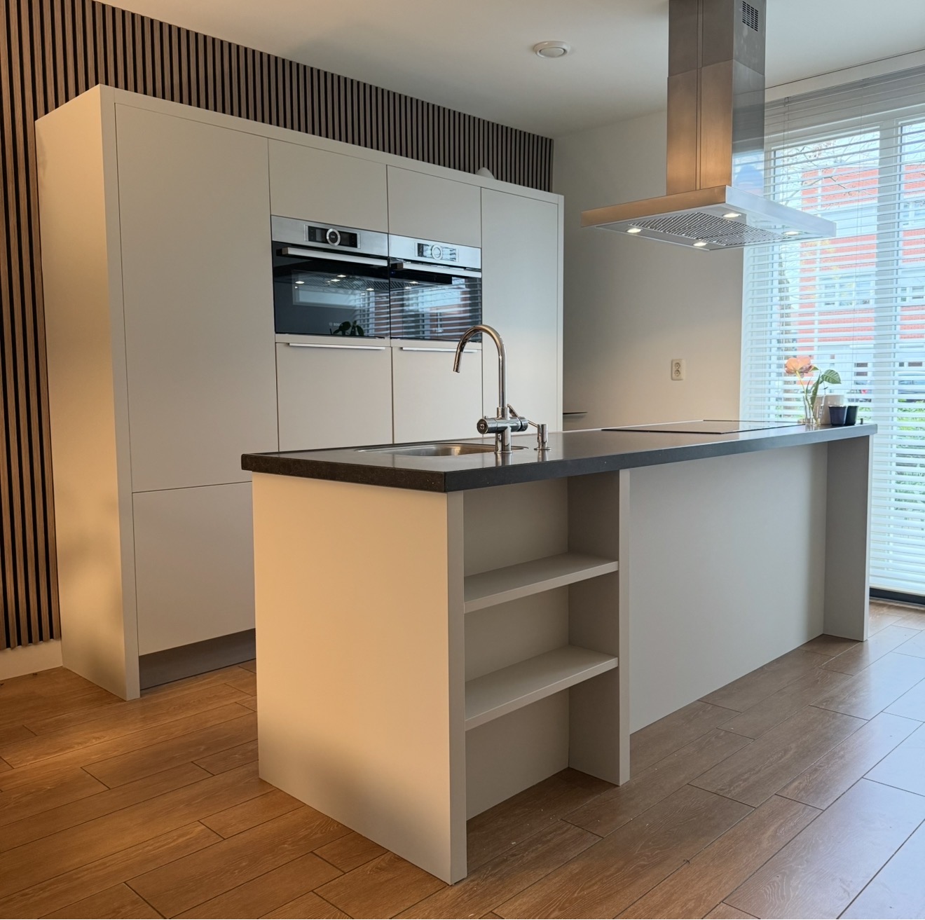 Lichte greeploze keuken met kookeiland en donkere houten wandlatten