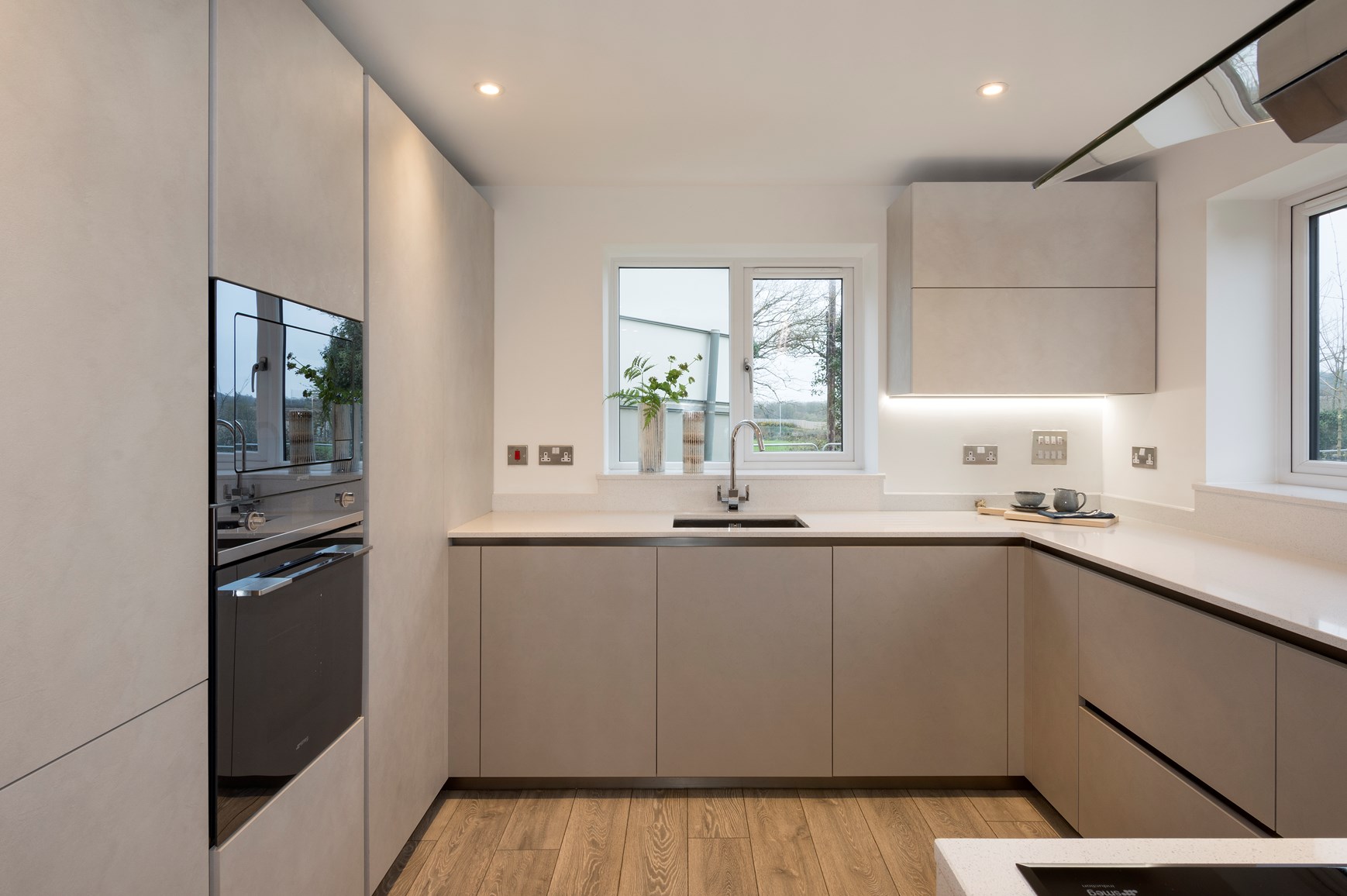 Rustige taupekleurige keuken met greeploze fronten en houten vloer